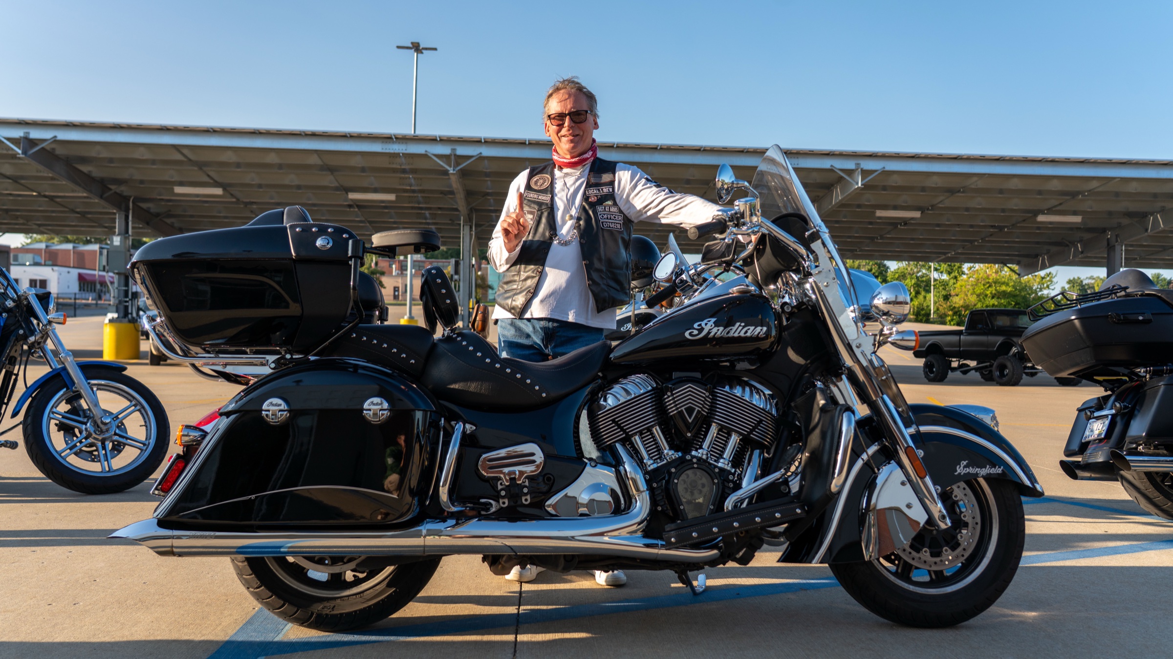 An EWRC1 member in his club vest standing proudly behind his Indian Chief motorcycle at the IBEW Local 1 parking lot.